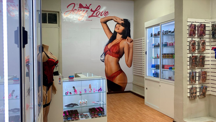 jenylove-vina-interior Interior de la tienda JenyLove en Viña del Mar con estanterías de productos íntimos y luz cálida.